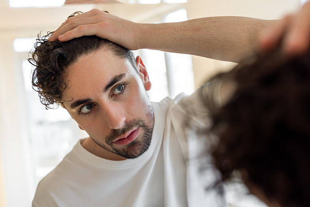 man looking at his hair in front of mirror with serious face